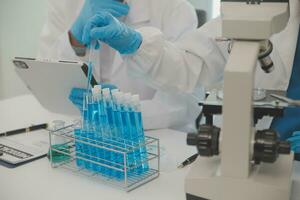 Health care researchers working in life science laboratory. Young female research scientist and senior male supervisor preparing and analyzing microscope slides in research lab. photo