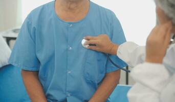 Close up of Female Doctor using stethoscope putting beat heart diagnose with patient in examination room at a hospital, check-up body, Medical and Health Care Concept. photo