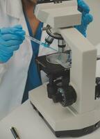 Health care researchers working in life science laboratory. Young female research scientist and senior male supervisor preparing and analyzing microscope slides in research lab. photo