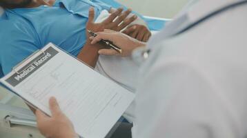 Close up of doctor sitting on bedside of male patient in hospital photo