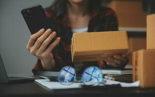 mujer de negocios puesta en marcha empresaria de pequeña empresa sme éxito. mujer independiente que trabaja en casa con entrega de paquetes en línea. concepto de entrega de pymes y embalajes foto