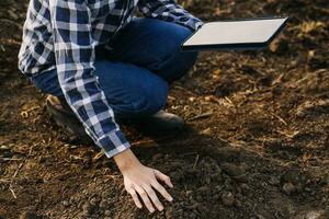 Male hands touching soil on the field. Expert hand of farmer checking soil health before growth a seed of vegetable or plant seedling. Business or ecology concept. photo