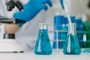 Young scientists conducting research investigations in a medical laboratory, a researcher in the foreground is using a microscope photo