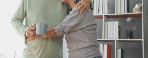 Happy old couple holding cup of hot tea while enjoying leisure time together at the home photo