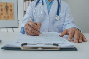 Lets set up an appointment for next week. Cropped shot of a young male doctor going through medical records with his senior male patient. photo