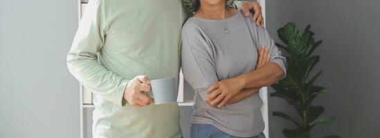 Happy old couple holding cup of hot tea while enjoying leisure time together at the home photo