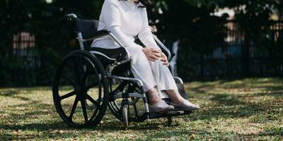 Asian young woman nurse at nursing home take care disabled senior man. Caregiver doctor serve physical therapy for older elderly patient to exercise and practice walking on walker or cane at backyard. photo