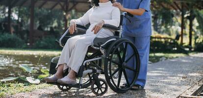 Asian young woman nurse at nursing home take care disabled senior man. Caregiver doctor serve physical therapy for older elderly patient to exercise and practice walking on walker or cane at backyard. photo