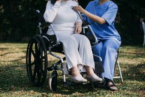 Asian young woman nurse at nursing home take care disabled senior man. Caregiver doctor serve physical therapy for older elderly patient to exercise and practice walking on walker or cane at backyard. photo