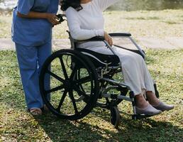 Asian young woman nurse at nursing home take care disabled senior man. Caregiver doctor serve physical therapy for older elderly patient to exercise and practice walking on walker or cane at backyard. photo