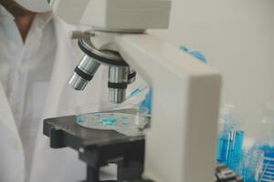 Health care researchers working in life science laboratory. Young female research scientist and senior male supervisor preparing and analyzing microscope slides in research lab. photo