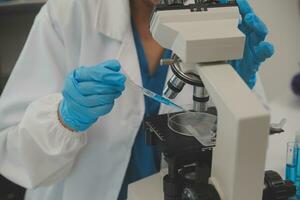 Health care researchers working in life science laboratory. Young female research scientist and senior male supervisor preparing and analyzing microscope slides in research lab. photo