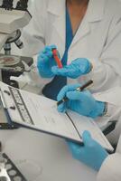 investigadores de atención médica que trabajan en el laboratorio de ciencias de la vida. joven científica investigadora y supervisora masculina senior preparando y analizando portaobjetos de microscopio en el laboratorio de investigación. foto