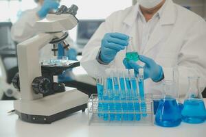 Health care researchers working in life science laboratory. Young female research scientist and senior male supervisor preparing and analyzing microscope slides in research lab. photo