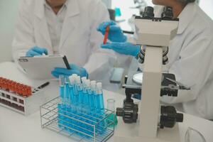 Health care researchers working in life science laboratory. Young female research scientist and senior male supervisor preparing and analyzing microscope slides in research lab. photo