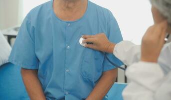 Close up of Female Doctor using stethoscope putting beat heart diagnose with patient in examination room at a hospital, check-up body, Medical and Health Care Concept. photo