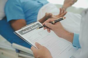 Close up of doctor sitting on bedside of male patient in hospital photo