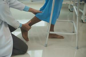 young asian physical therapist working with senior woman on walking with a walker photo