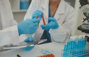 Health care researchers working in life science laboratory. Young female research scientist and senior male supervisor preparing and analyzing microscope slides in research lab. photo