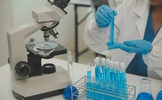Health care researchers working in life science laboratory. Young female research scientist and senior male supervisor preparing and analyzing microscope slides in research lab. photo