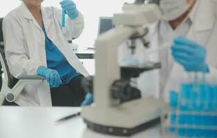 Health care researchers working in life science laboratory. Young female research scientist and senior male supervisor preparing and analyzing microscope slides in research lab. photo