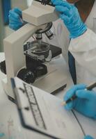 Health care researchers working in life science laboratory. Young female research scientist and senior male supervisor preparing and analyzing microscope slides in research lab. photo