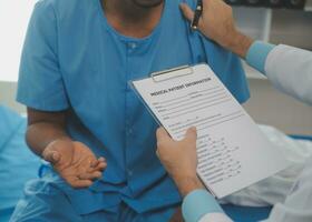 Close up of doctor sitting on bedside of male patient in hospital photo