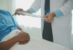 Close up of doctor sitting on bedside of male patient in hospital photo