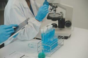 Health care researchers working in life science laboratory. Young female research scientist and senior male supervisor preparing and analyzing microscope slides in research lab. photo