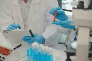 Health care researchers working in life science laboratory. Young female research scientist and senior male supervisor preparing and analyzing microscope slides in research lab. photo