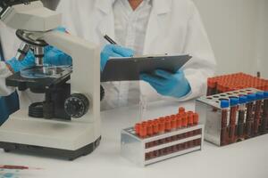 Health care researchers working in life science laboratory. Young female research scientist and senior male supervisor preparing and analyzing microscope slides in research lab. photo