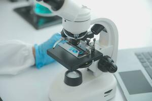 Health care researchers working in life science laboratory. Young female research scientist and senior male supervisor preparing and analyzing microscope slides in research lab. photo