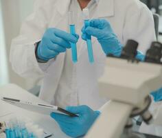 Health care researchers working in life science laboratory. Young female research scientist and senior male supervisor preparing and analyzing microscope slides in research lab. photo
