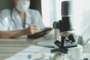 Young scientists conducting research investigations in a medical laboratory, a researcher in the foreground is using a microscope photo