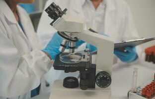 Health care researchers working in life science laboratory. Young female research scientist and senior male supervisor preparing and analyzing microscope slides in research lab. photo