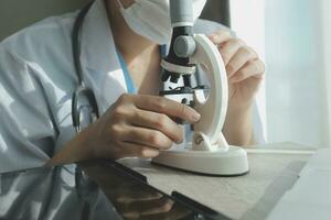 Young scientists conducting research investigations in a medical laboratory, a researcher in the foreground is using a microscope photo
