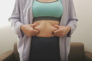 A woman shows an inflated thick belly, the concept of excess weight and weight loss photo