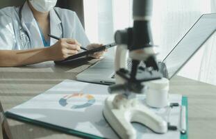 Young scientists conducting research investigations in a medical laboratory, a researcher in the foreground is using a microscope photo