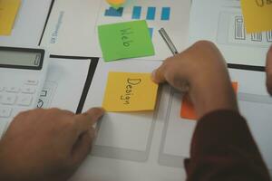 Close up ux developer and ui designer brainstorming about mobile app interface wireframe design on table with customer breif and color code at modern office.Creative digital development agency photo