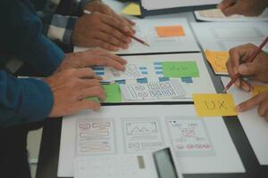 Close up ux developer and ui designer brainstorming about mobile app interface wireframe design on table with customer breif and color code at modern office.Creative digital development agency photo