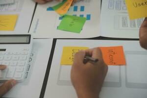 Close up ux developer and ui designer brainstorming about mobile app interface wireframe design on table with customer breif and color code at modern office.Creative digital development agency photo