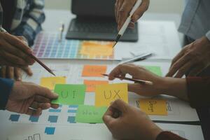 Close up ux developer and ui designer brainstorming about mobile app interface wireframe design on table with customer breif and color code at modern office.Creative digital development agency photo