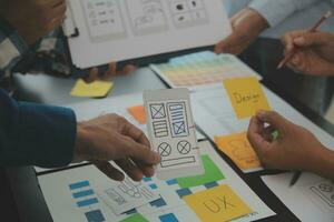 Close up ux developer and ui designer brainstorming about mobile app interface wireframe design on table with customer breif and color code at modern office.Creative digital development agency photo