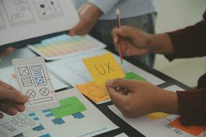 Close up ux developer and ui designer brainstorming about mobile app interface wireframe design on table with customer breif and color code at modern office.Creative digital development agency photo