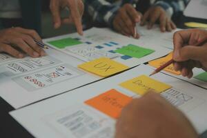 Close up ux developer and ui designer brainstorming about mobile app interface wireframe design on table with customer breif and color code at modern office.Creative digital development agency photo