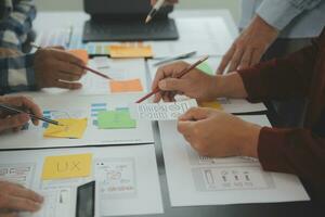 Close up ux developer and ui designer brainstorming about mobile app interface wireframe design on table with customer breif and color code at modern office.Creative digital development agency photo