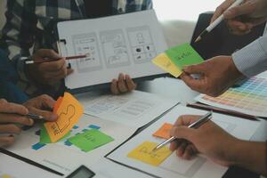 Close up ux developer and ui designer brainstorming about mobile app interface wireframe design on table with customer breif and color code at modern office.Creative digital development agency photo