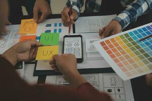 Close up ux developer and ui designer brainstorming about mobile app interface wireframe design on table with customer breif and color code at modern office.Creative digital development agency photo