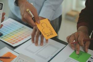 Close up ux developer and ui designer brainstorming about mobile app interface wireframe design on table with customer breif and color code at modern office.Creative digital development agency photo