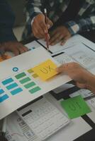 Close up ux developer and ui designer brainstorming about mobile app interface wireframe design on table with customer breif and color code at modern office.Creative digital development agency photo